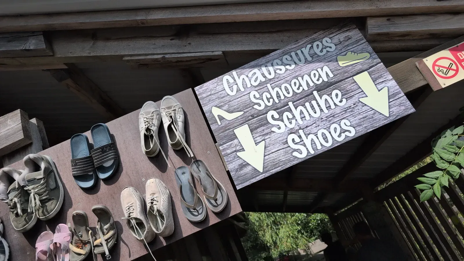 Panneau multilingue invitant à déposer ses chaussures avant le sentier pieds nus